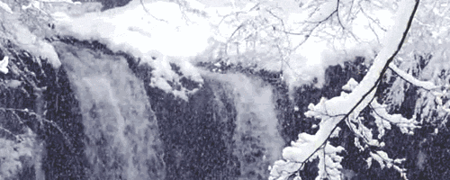 Water flows over a cliff as a light snowfall returns evaporated water to Earth.